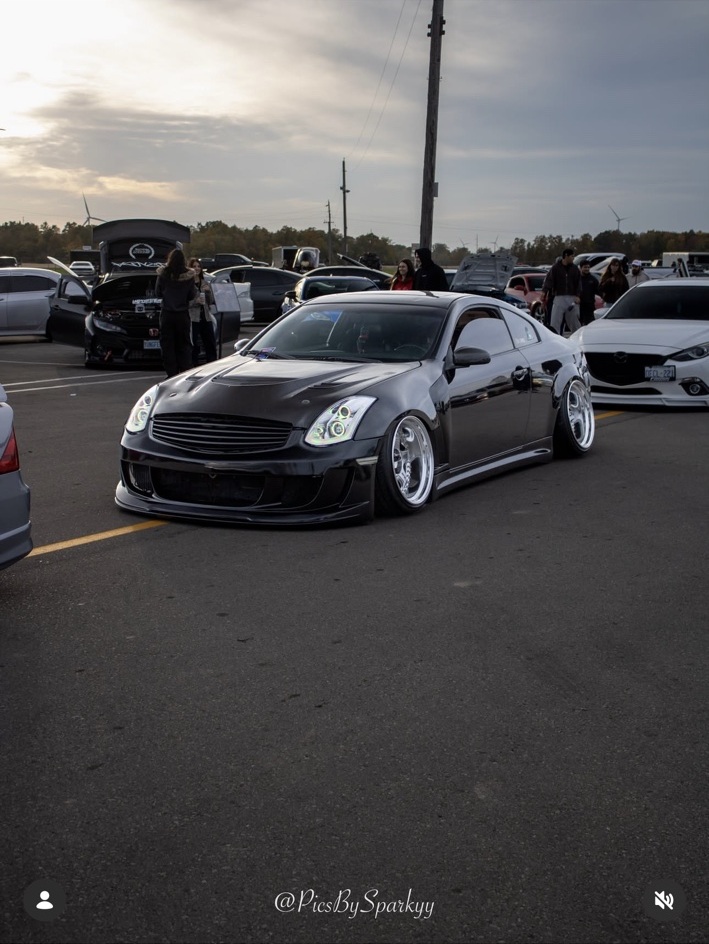 Low black Infiniti coupe with polished wheels at a car meet, photographed by Connor